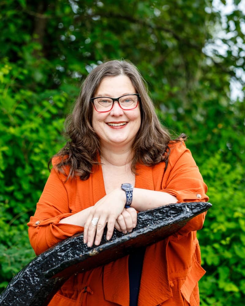 Samantha Scholefield leaning on a railing with trees behind her.